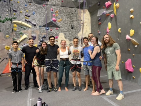 Group picture of climbers in the RocVenture and tall climbing wall is the background