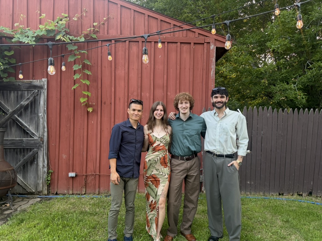 4 young adults in the picture (1 lady and 3 man) in the background of barn